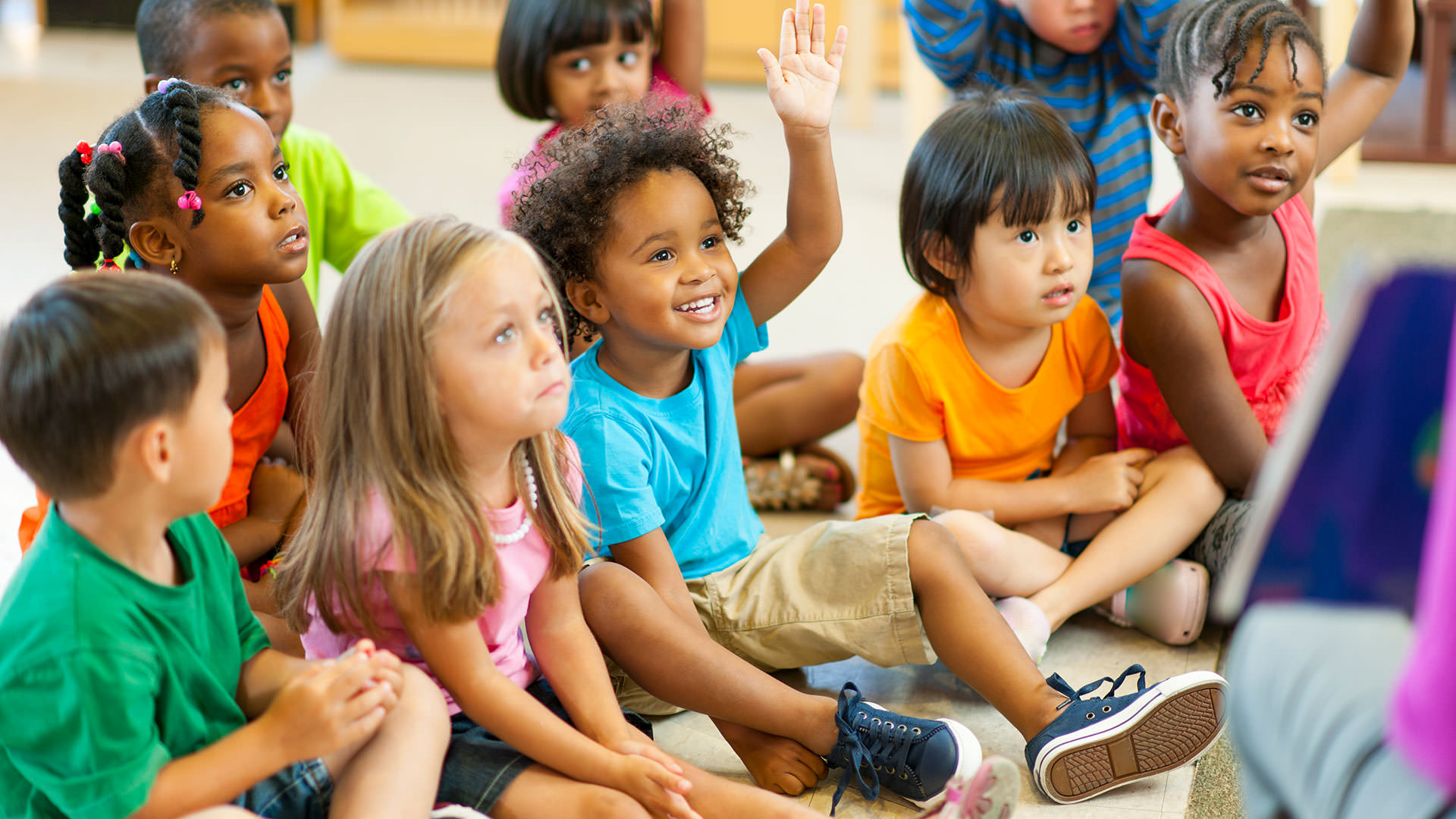 Child with hand up in classroom